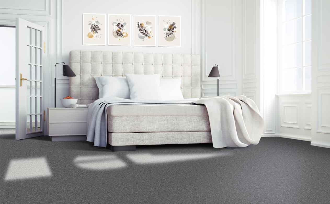 Bedroom with cream fabric bedframe and dark grey carpet.