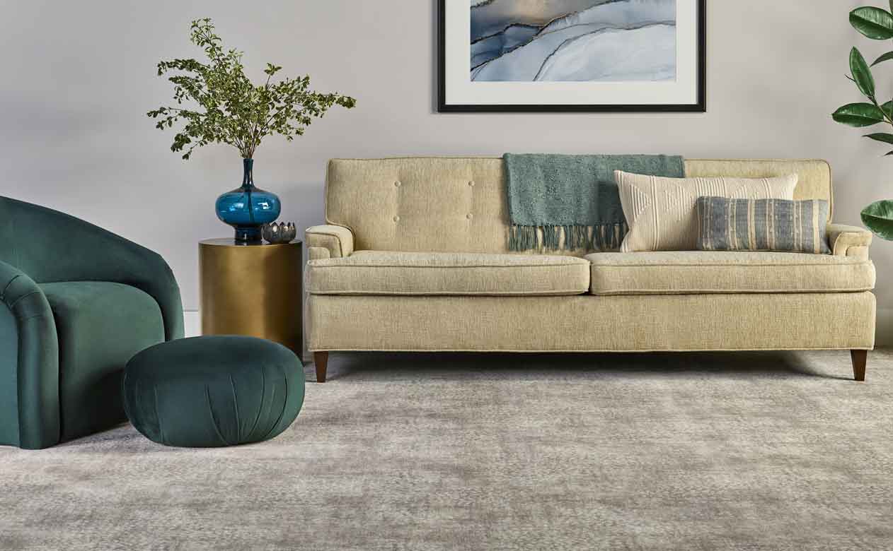 Neutral carpet in living area with tan mid centruy modern sofa and green armchair